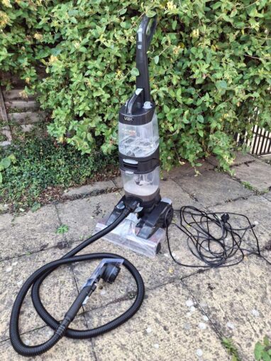 The carpet washer with hose and scrubbing hand tool attached.